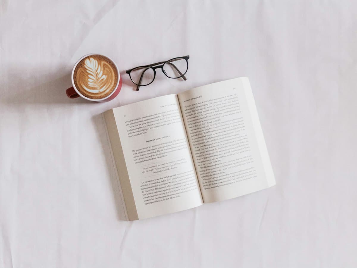Открытая книга, очки и капучино на светлой ткани